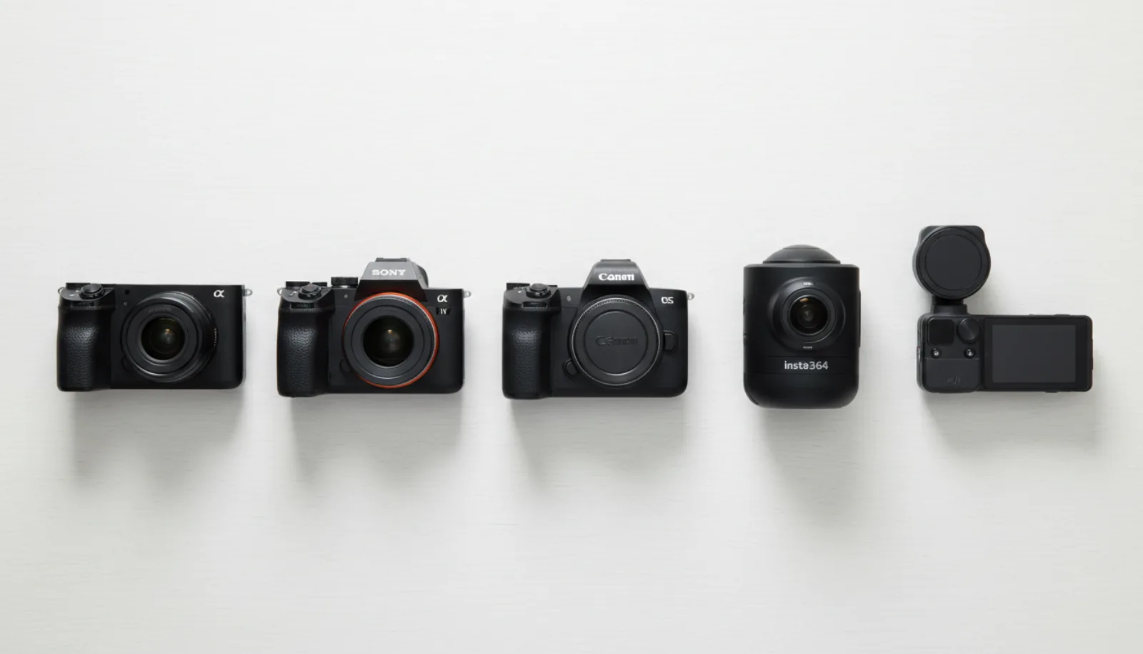 Five cameras flat-lay overhead on white wood: Sony A7C II compact full-frame mirrorless, Sony A7 IV, Canon EOS R8, Insta360 X4 360 camera, and DJI Pocket 3 with screen visible